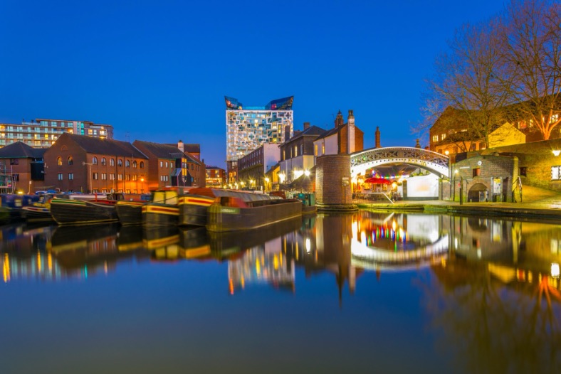 Birmingham canal at blue hour with The Cube and historic industrial buildings