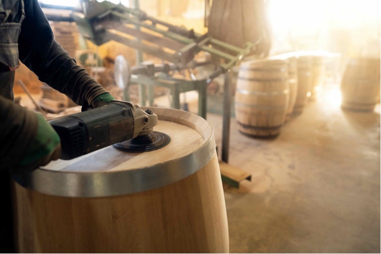 Worker sanding a wooden cask in a cooperage where wood dust may require effective exposure control