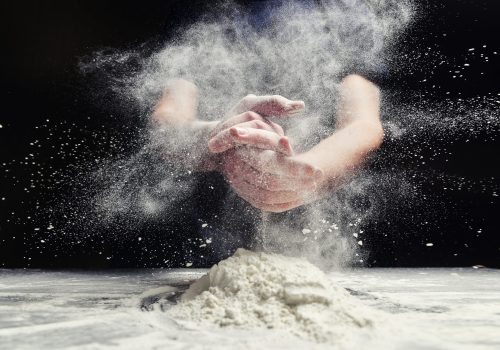 Chef, baker making splash with flour, freezing cloud of flour.